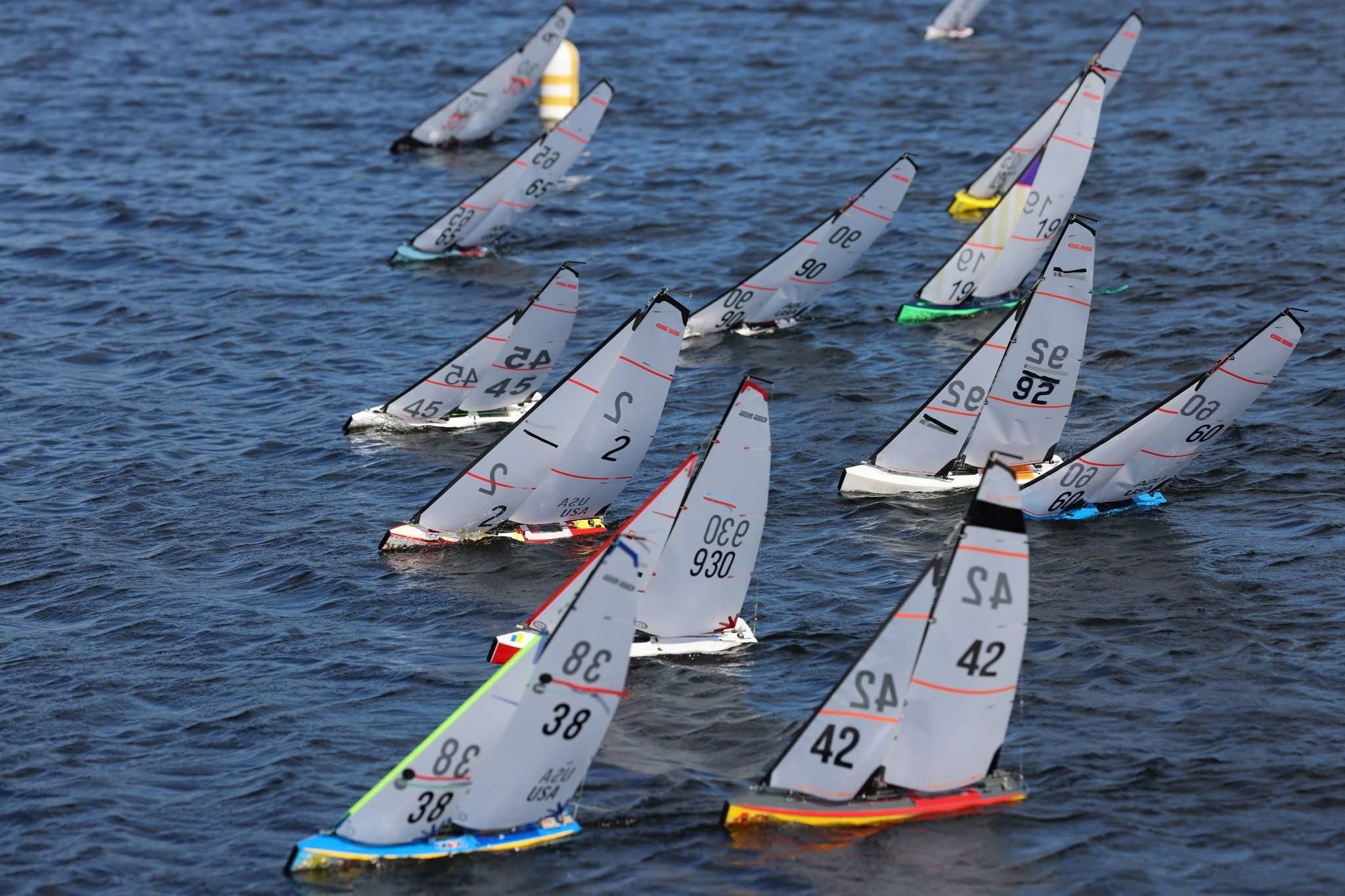 A fleet of radio controlled sailboats rounding a mark together on open water